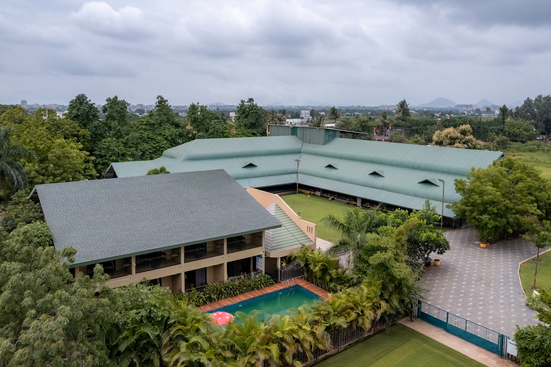 Aerial view of the villa, pool and banquet hall roof with the hills of Nashik behind