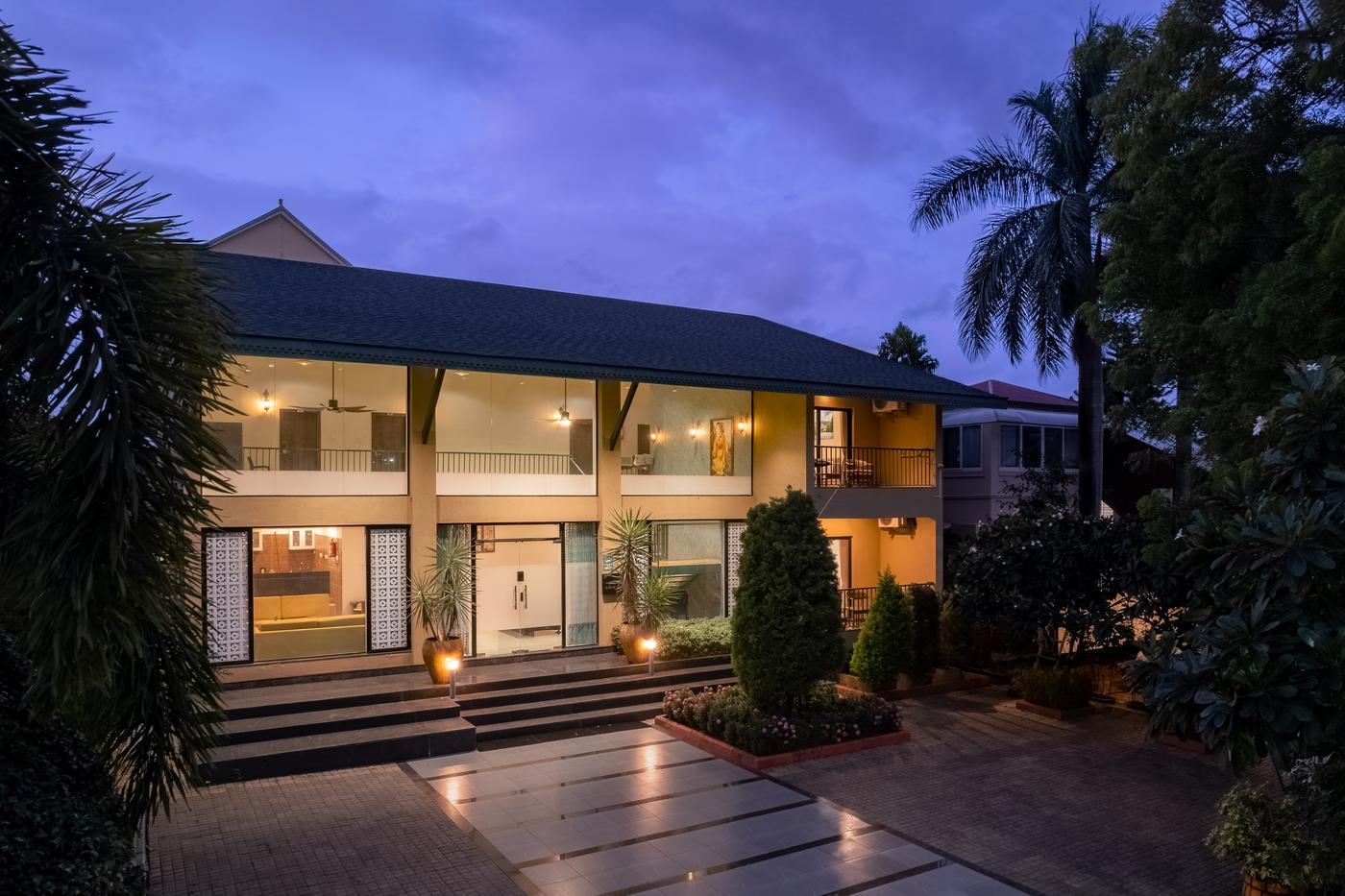 Amaltas Villa lit up at dusk under palms