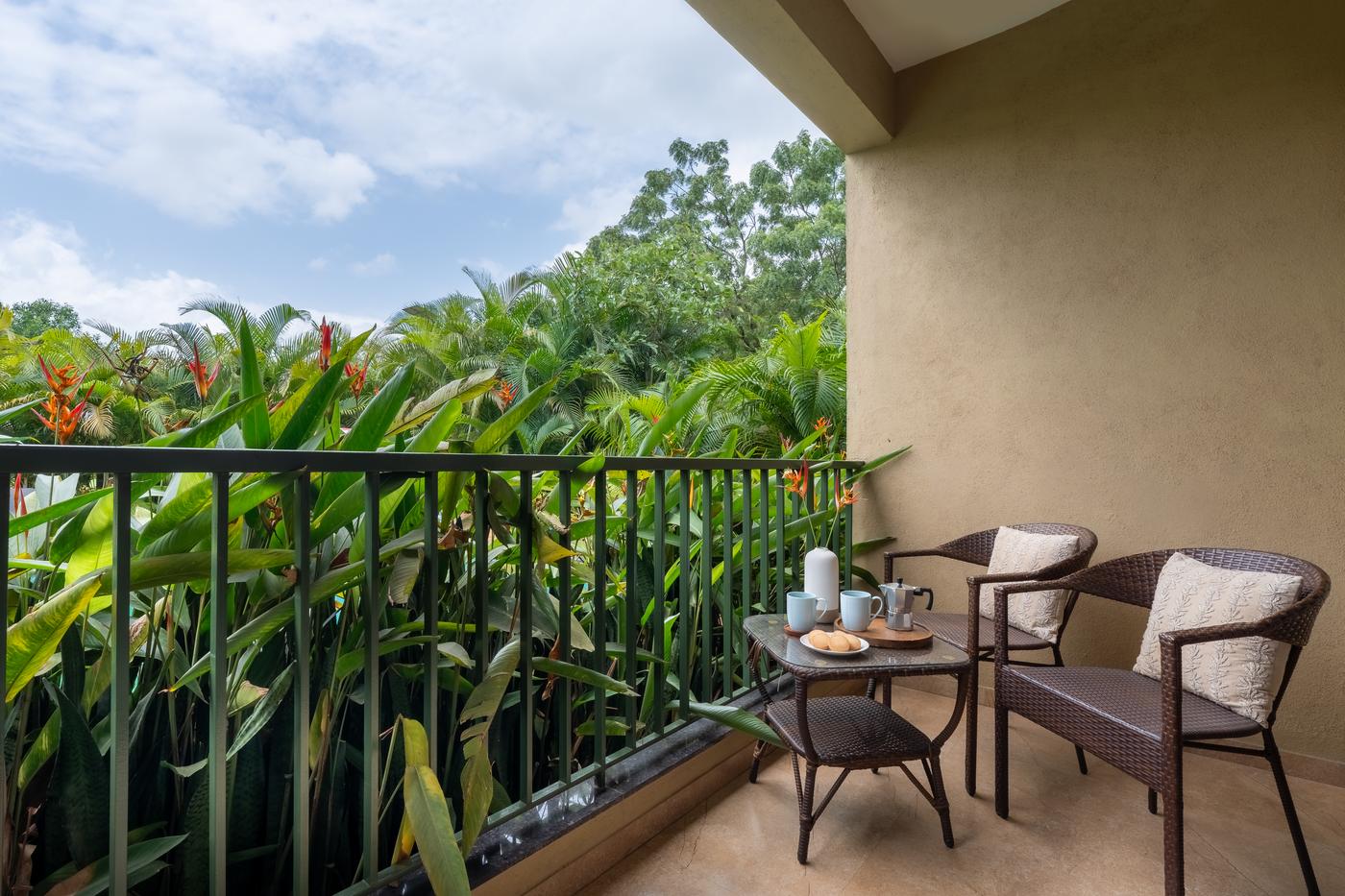 A room balcony with two chairs, coffee, and heliconias at the railing