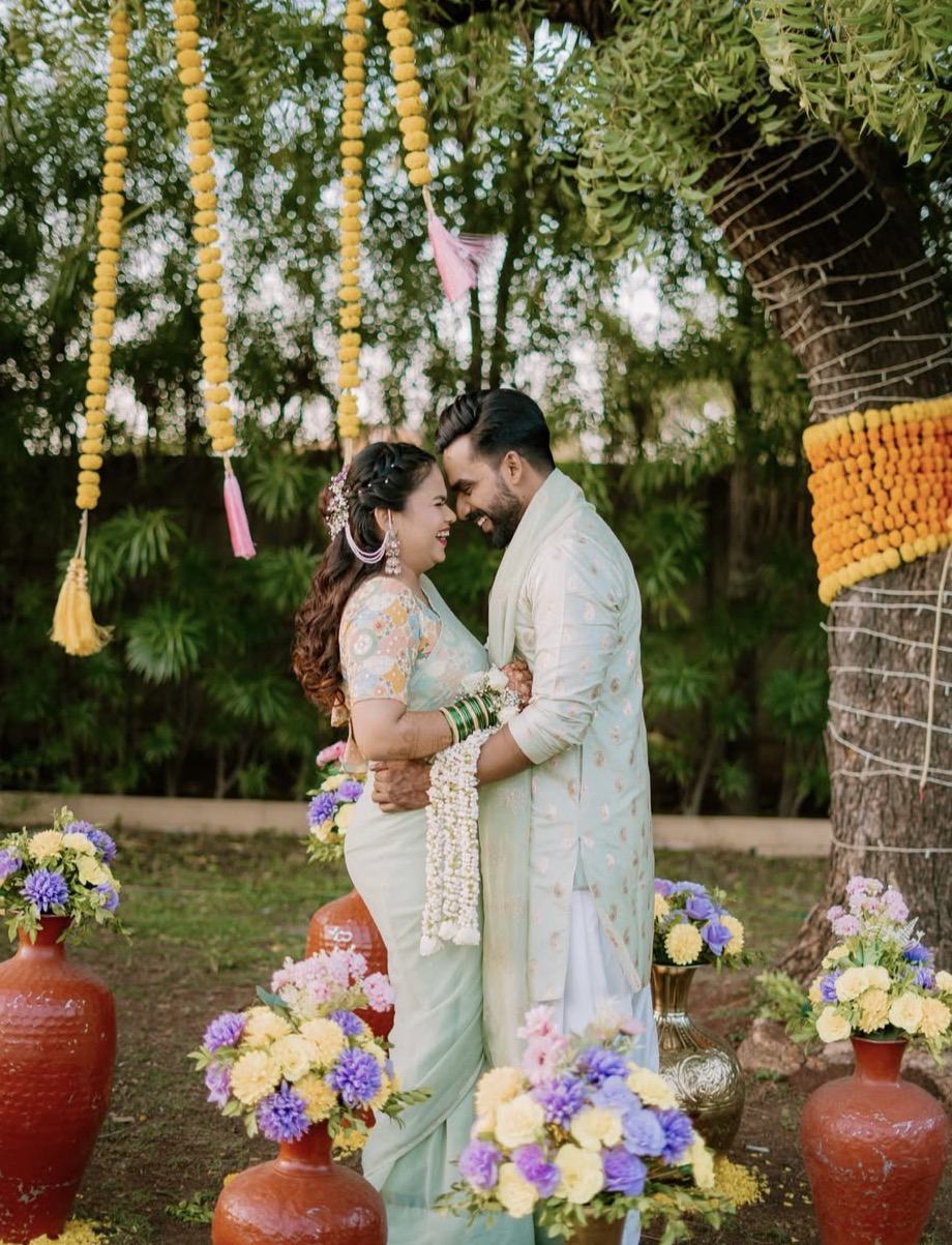 A couple forehead to forehead under marigold strings at their haldi