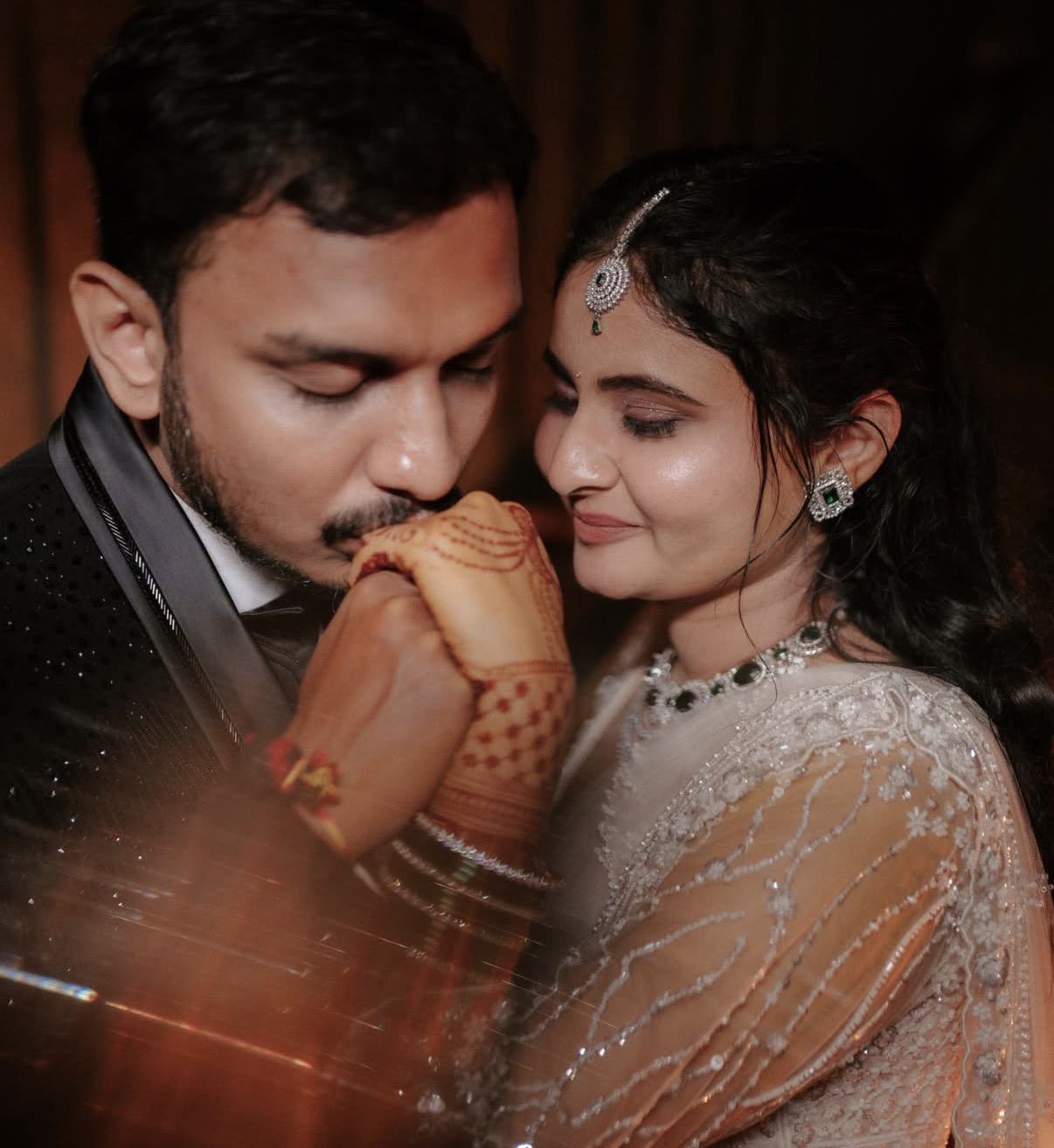A groom kissing the bride's mehendi hand, close and quiet