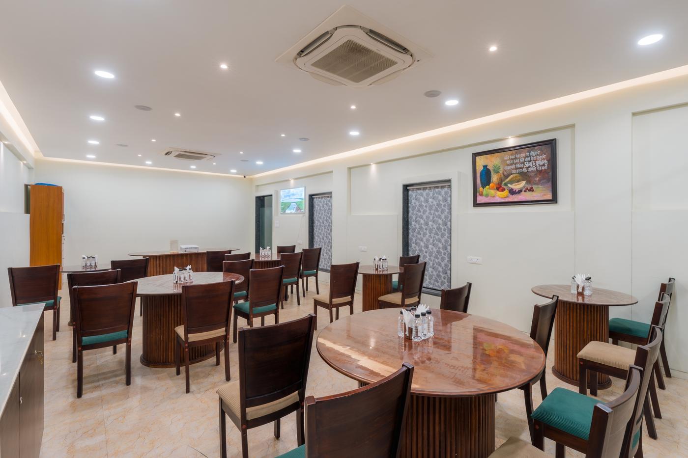 The dining hall with round wooden tables and green-cushioned chairs