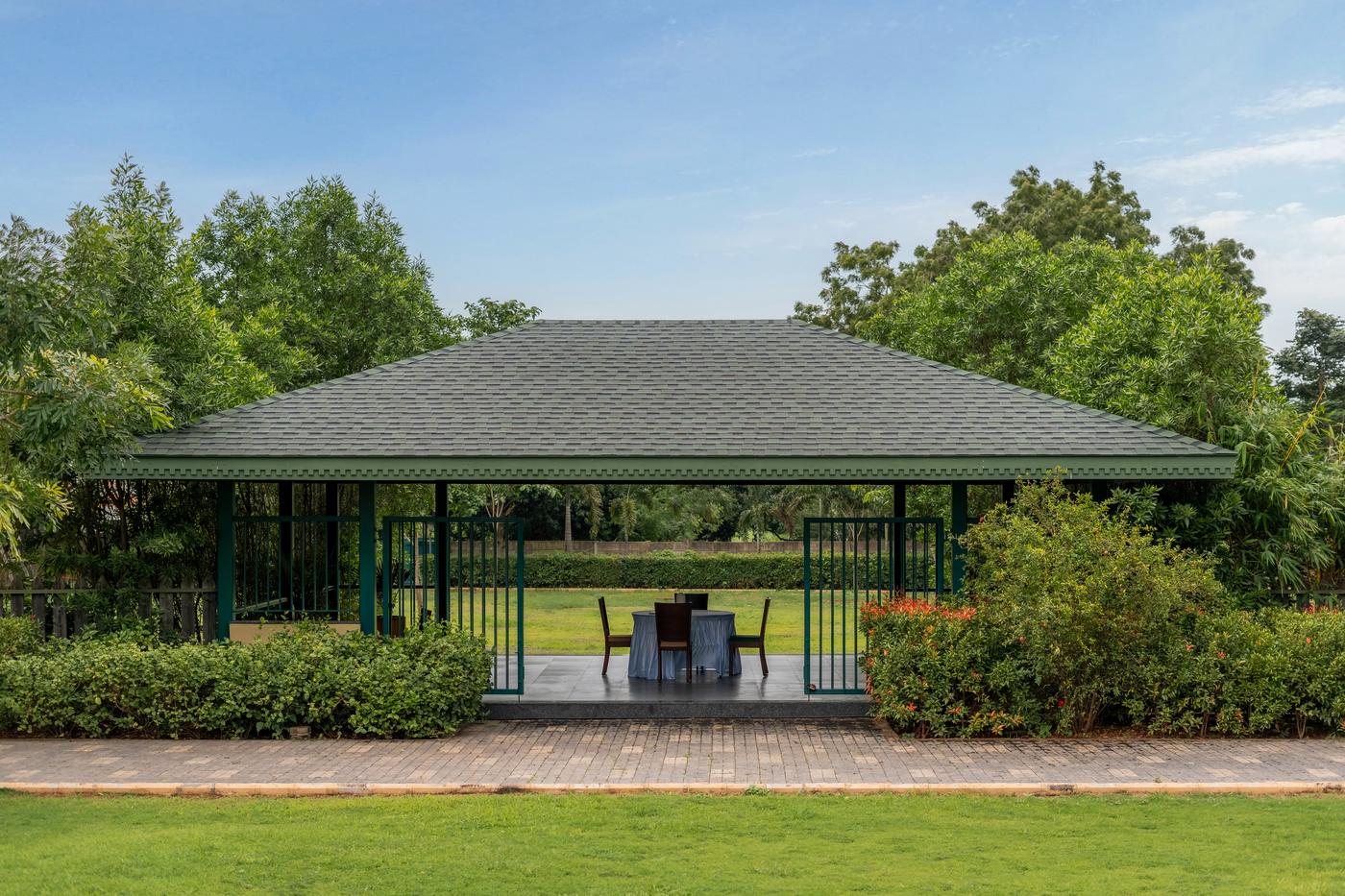 A garden gazebo with a single set table, framed by greenery