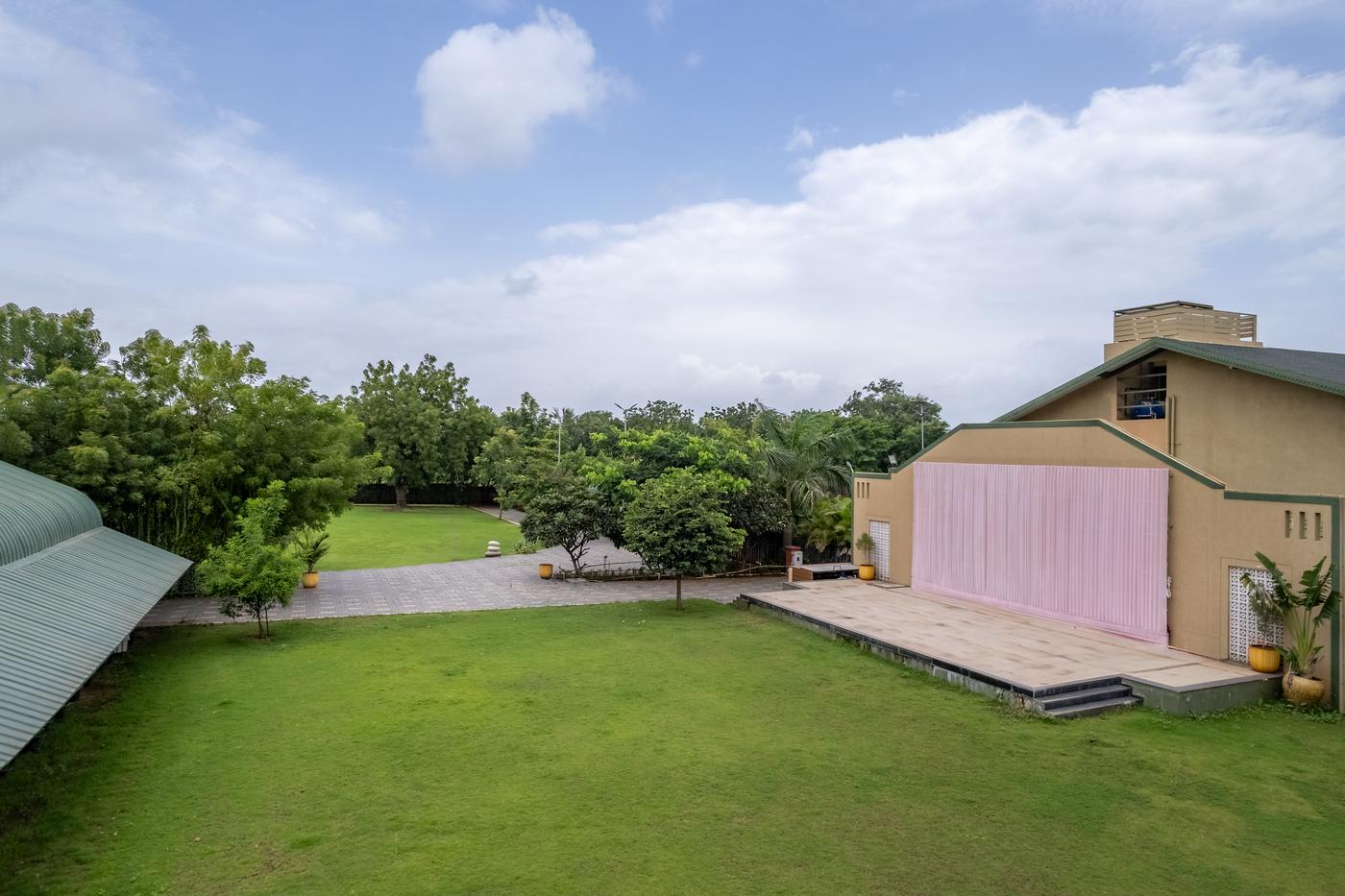 Harit-Lila lawn by day, with the stage building and old trees behind