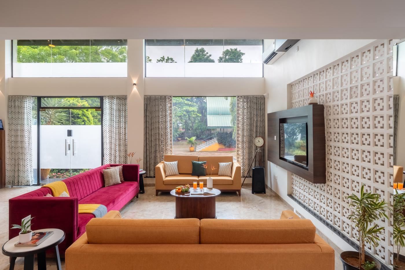 The villa lounge with a deep pink sofa and tall windows onto the garden