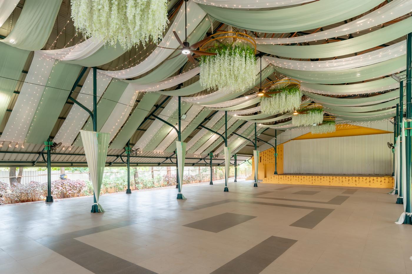 Inside Mangal-Vedika: a covered hall with draped ceilings, hanging florals and a stage