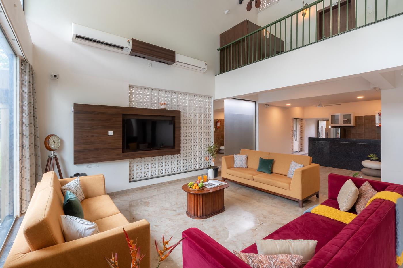 The double-height villa lounge with sofas, a jaali wall and a mezzanine above